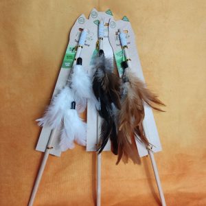 Three feather wand cat toys resting on an orange back ground.