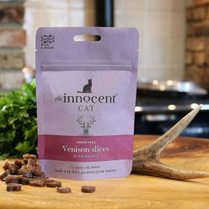 A packet of innocent cat venison treats on a kitchen work surface with a few treats by the side of the packet