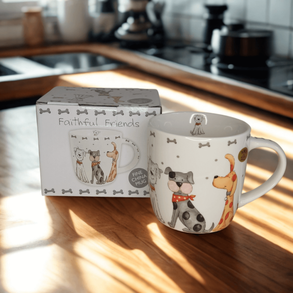 Faithful Friends fine china dog mug and box on a sunlit kitchen table. The mug shows colourful cartoon-style dogs wearing collars and scarves, surrounded by grey bones and dots.