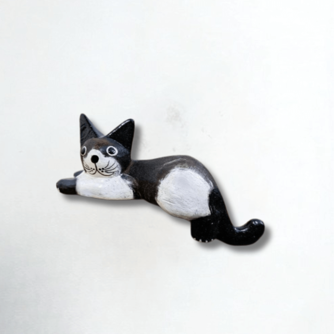 Hand-carved wooden black and white cat ornament in a lounging pose, photographed against a plain white background. Perfect decorative gift for cat lovers.