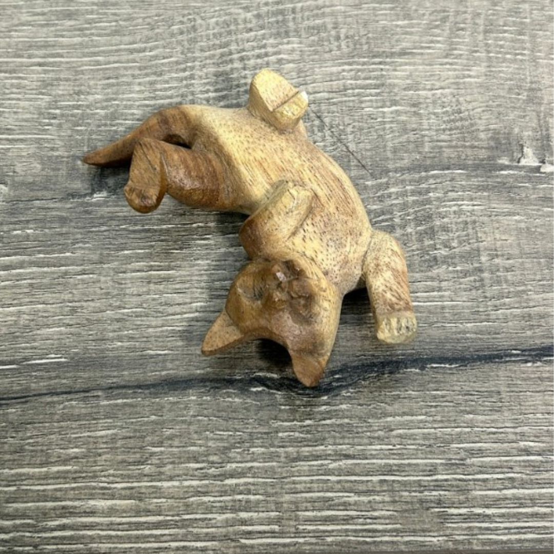 Handmade wooden cat carving lying on its back, crafted from natural wood and shown on a rustic wooden surface. A charming, eco-friendly home décor piece for cat lovers.