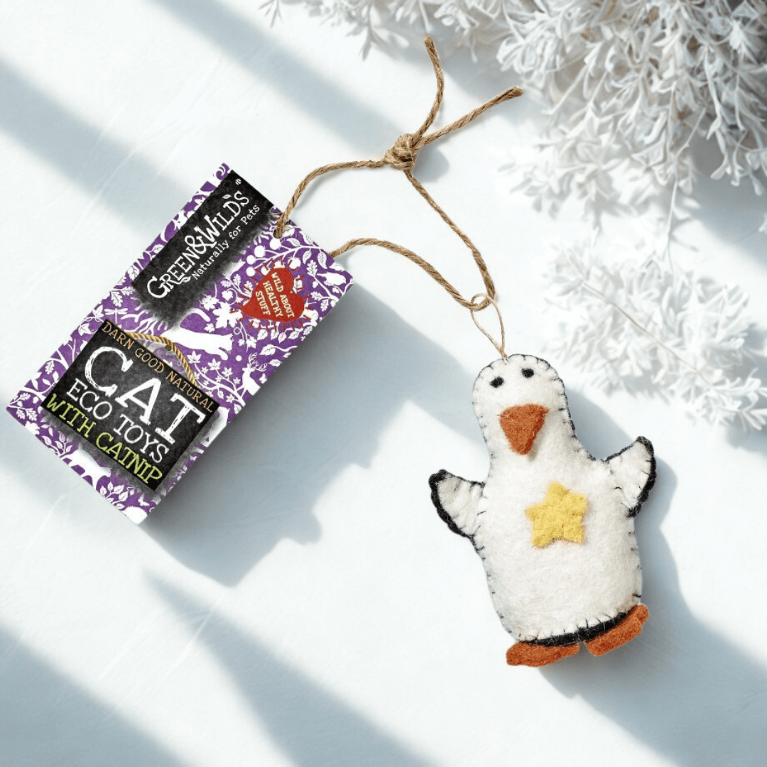 Wool felt penguin cat toy with catnip, displayed beside a Green & Wild’s tag and festive winter greenery.