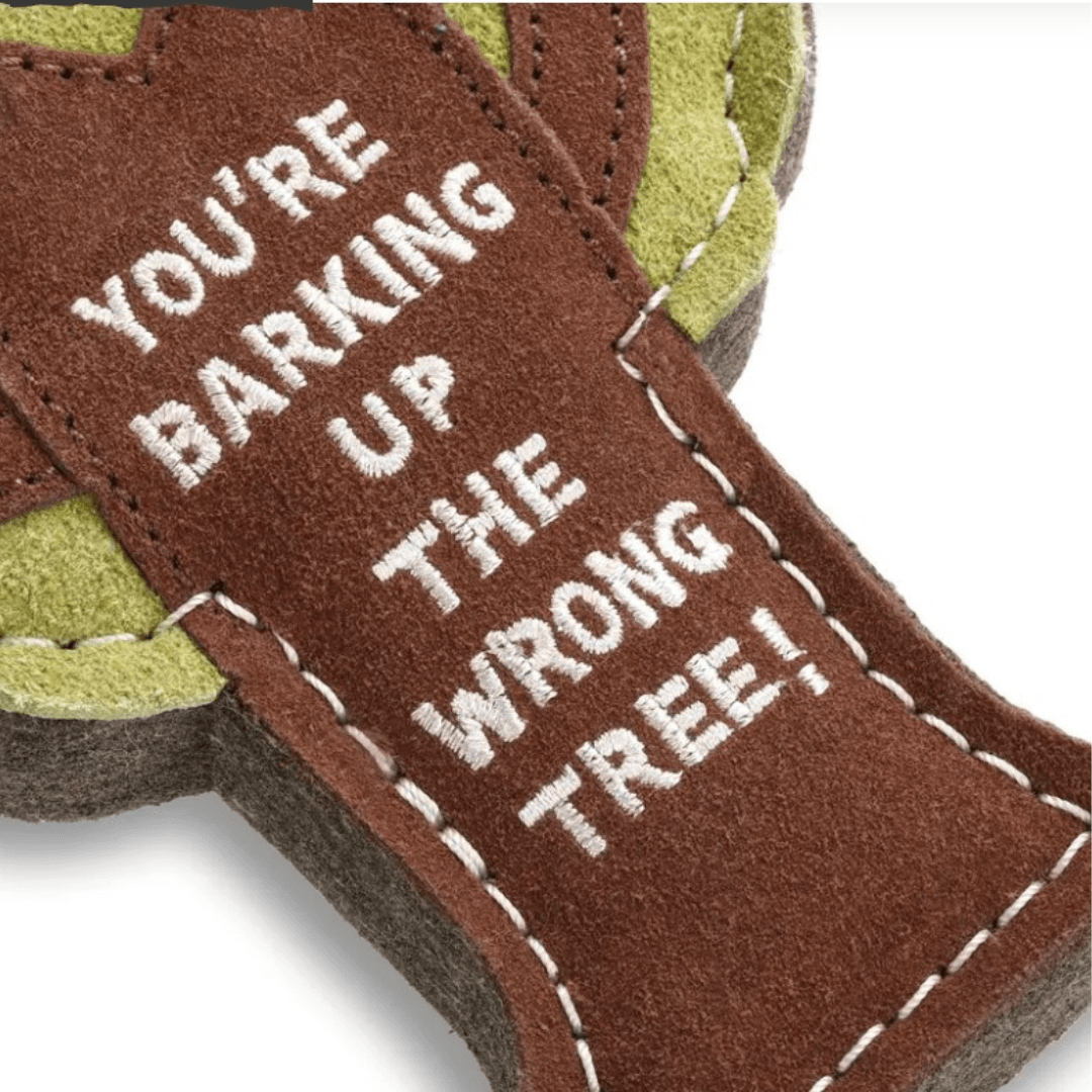 Close-up of eco dog toy showing brown suede trunk with white stitched text reading “You’re Barking Up the Wrong Tree.”