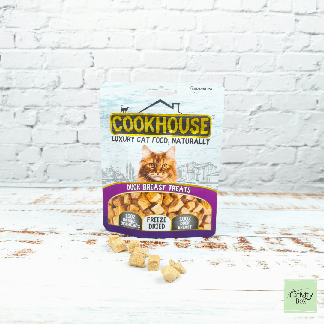 Cookhouse Freeze-Dried Duck Breast Cat Treats in pouch with freeze-dried duck cubes shown in front, natural grain-free cat treats on white wooden surface.