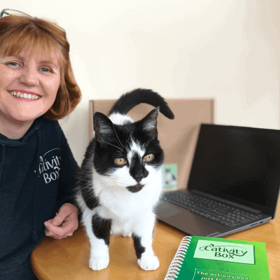 Angela and Lilly working on a wooden desk with a cativity box diary at the front of the photo. Angela is smiling